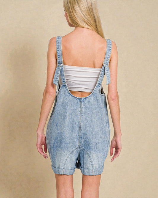 Person wearing denim overalls on a beige background