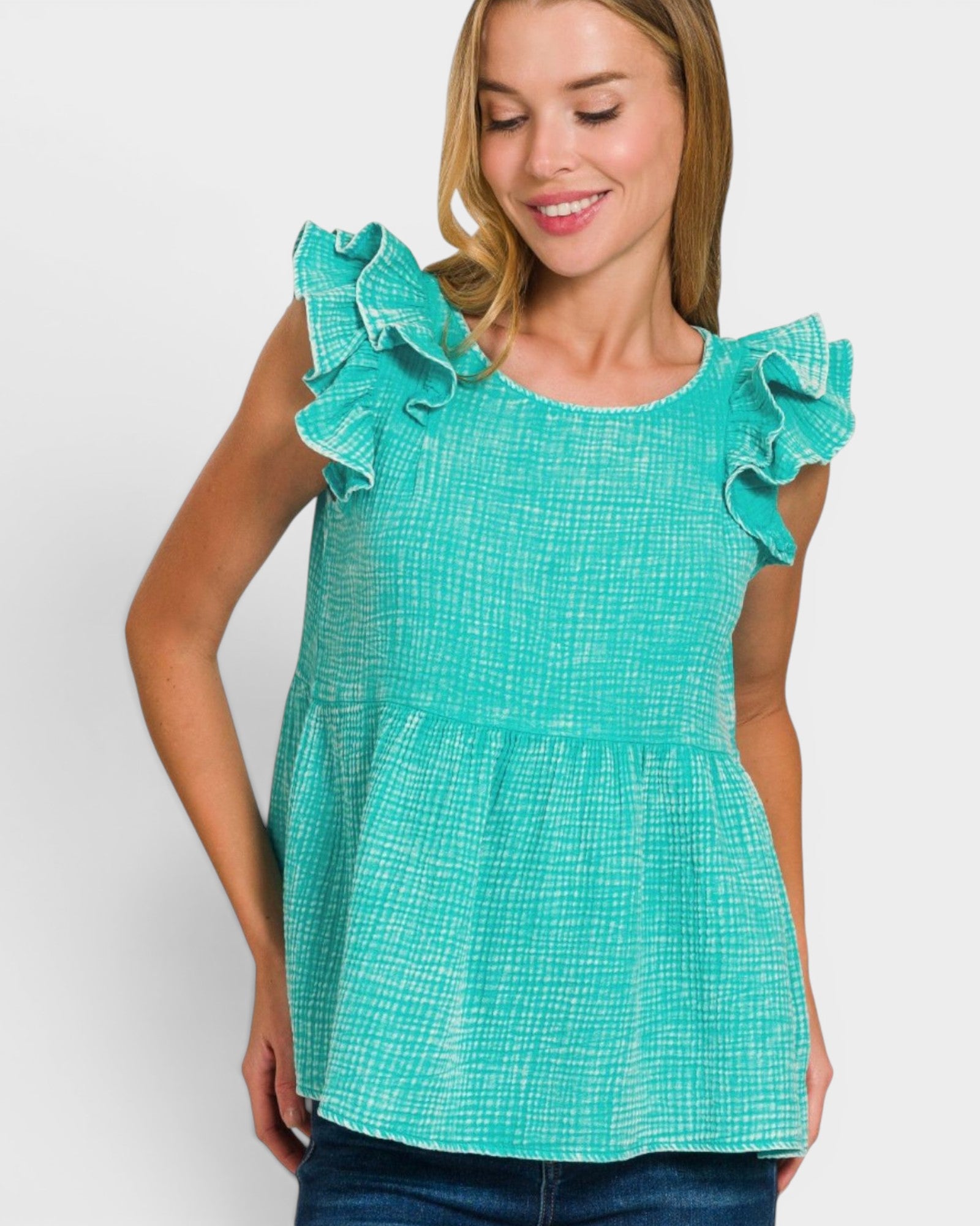 Woman wearing a teal top with ruffled shoulders on a white background