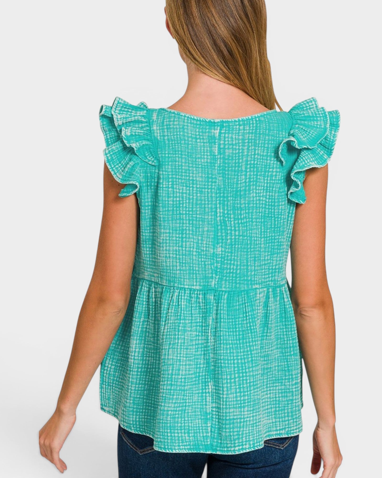 Woman wearing a teal checkered top with ruffled sleeves on a white background