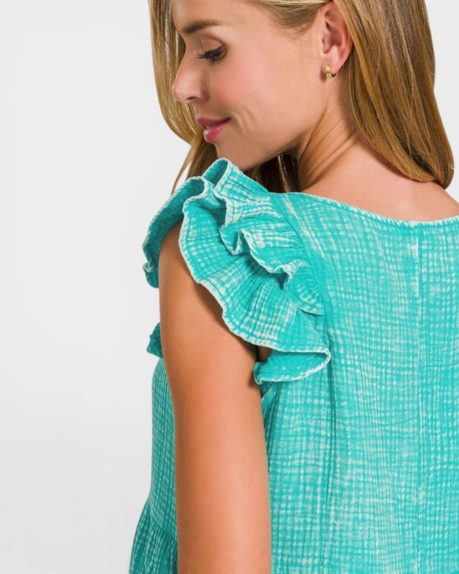 Close-up of a person wearing a teal top with ruffled shoulders on a white background