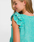 Close-up of a person wearing a teal top with ruffled shoulders on a white background