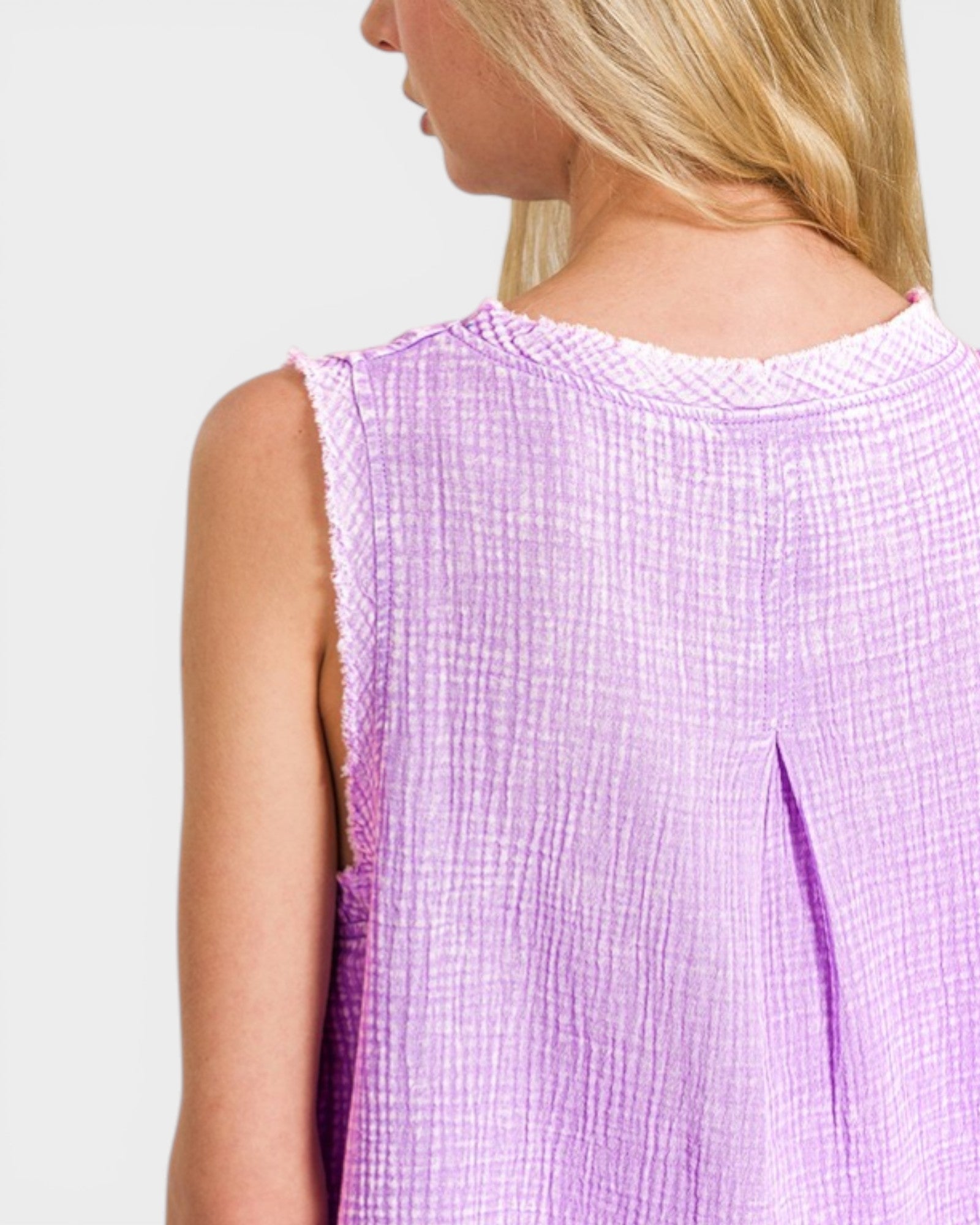 Person wearing a light purple sleeveless top on a plain background