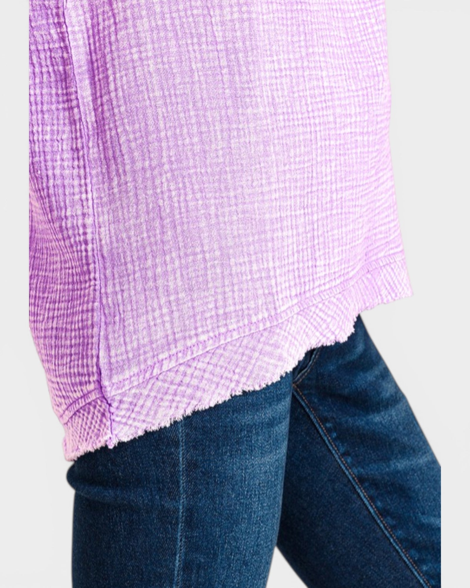 Close-up of a person wearing a purple checkered shirt and blue jeans on a light gray background