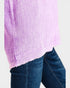 Close-up of a person wearing a purple checkered shirt and blue jeans on a light gray background