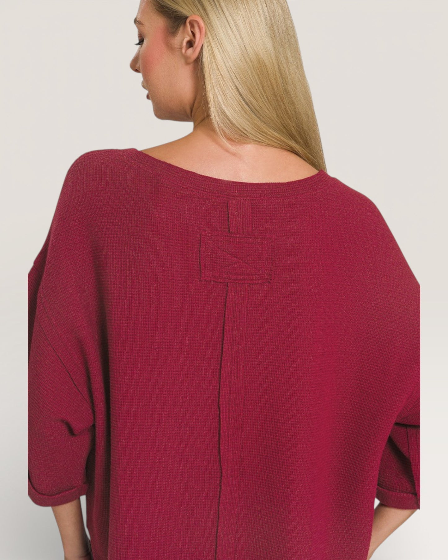 Woman wearing a burgundy top with a plain background