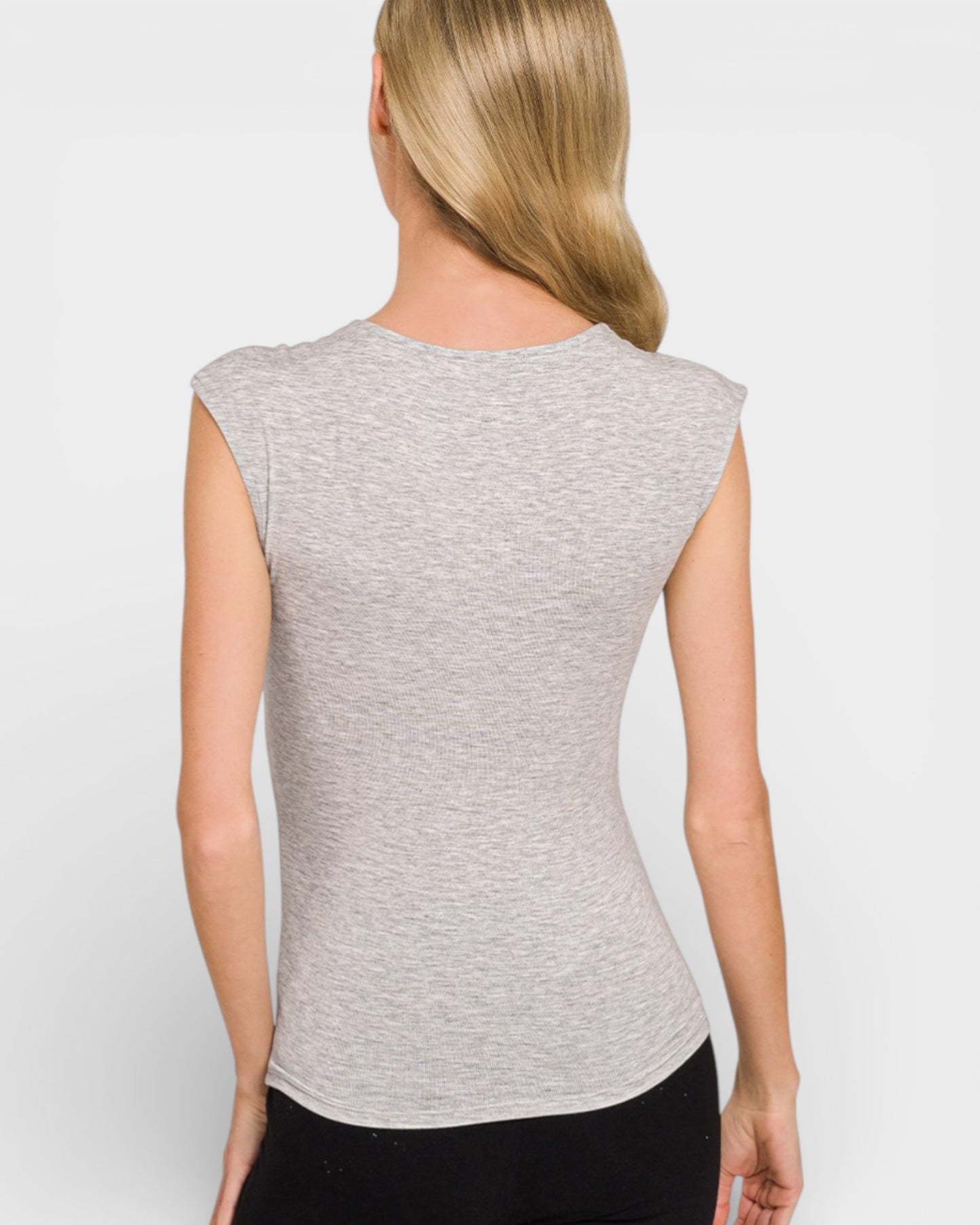 Woman wearing a gray sleeveless top against a white background