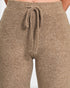 Close-up of a person wearing heathered taupe-brown knit pants with a drawstring waistband, shown against a plain light background.