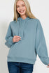 Woman wearing a light blue hoodie against a solid blue background