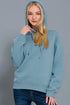 Woman wearing a light blue hoodie against a gray background