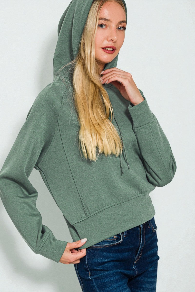 Woman wearing a green hoodie against a white background