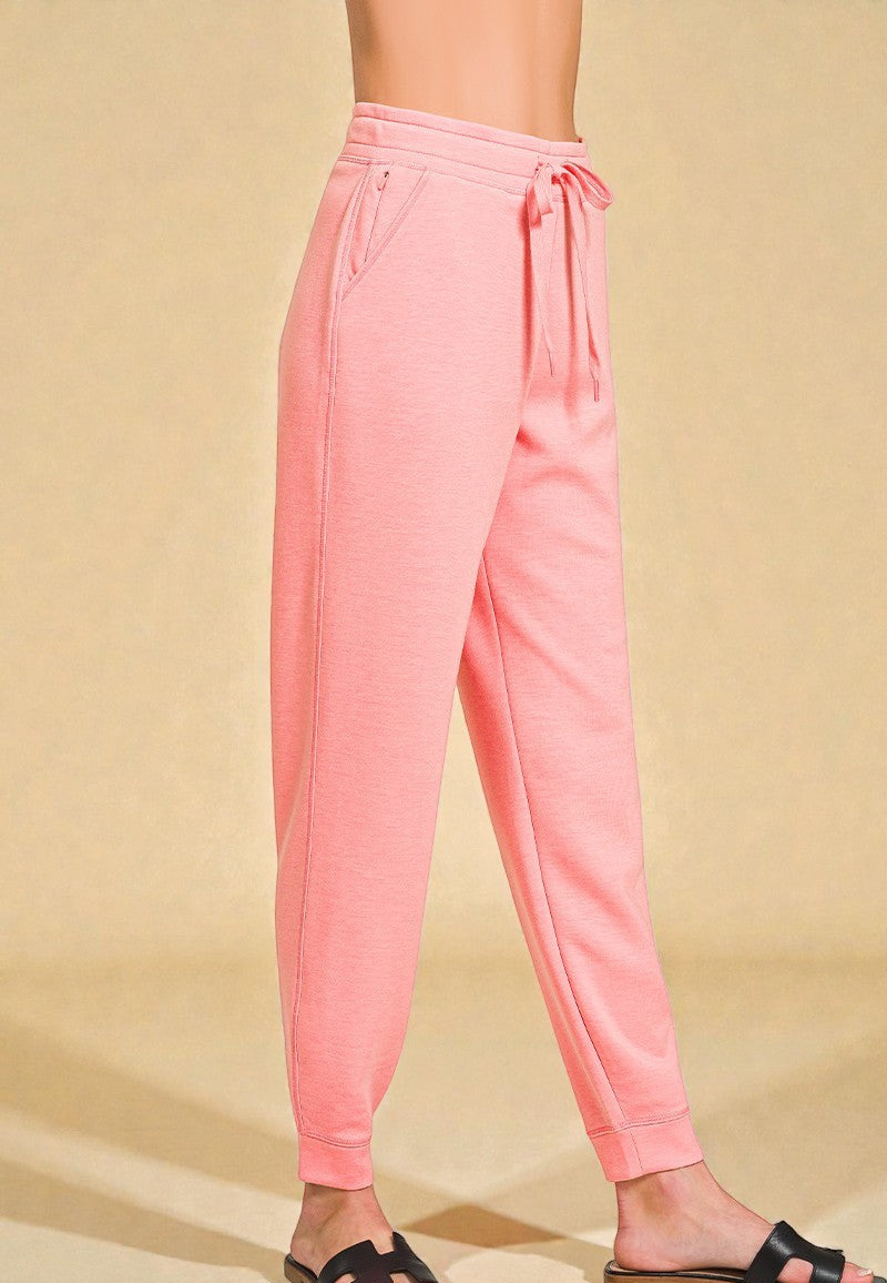 Pink sweatpants worn by a person on a beige background
