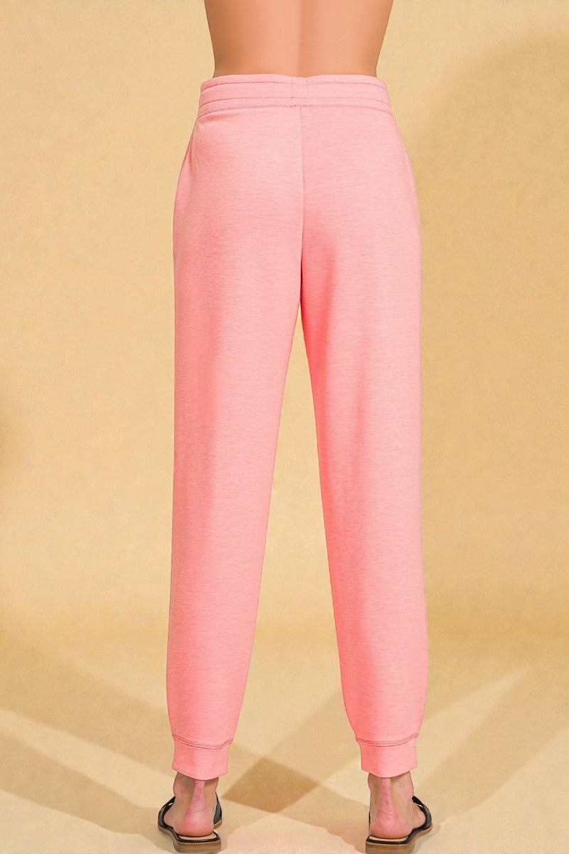 Pink sweatpants worn by a person on a beige background