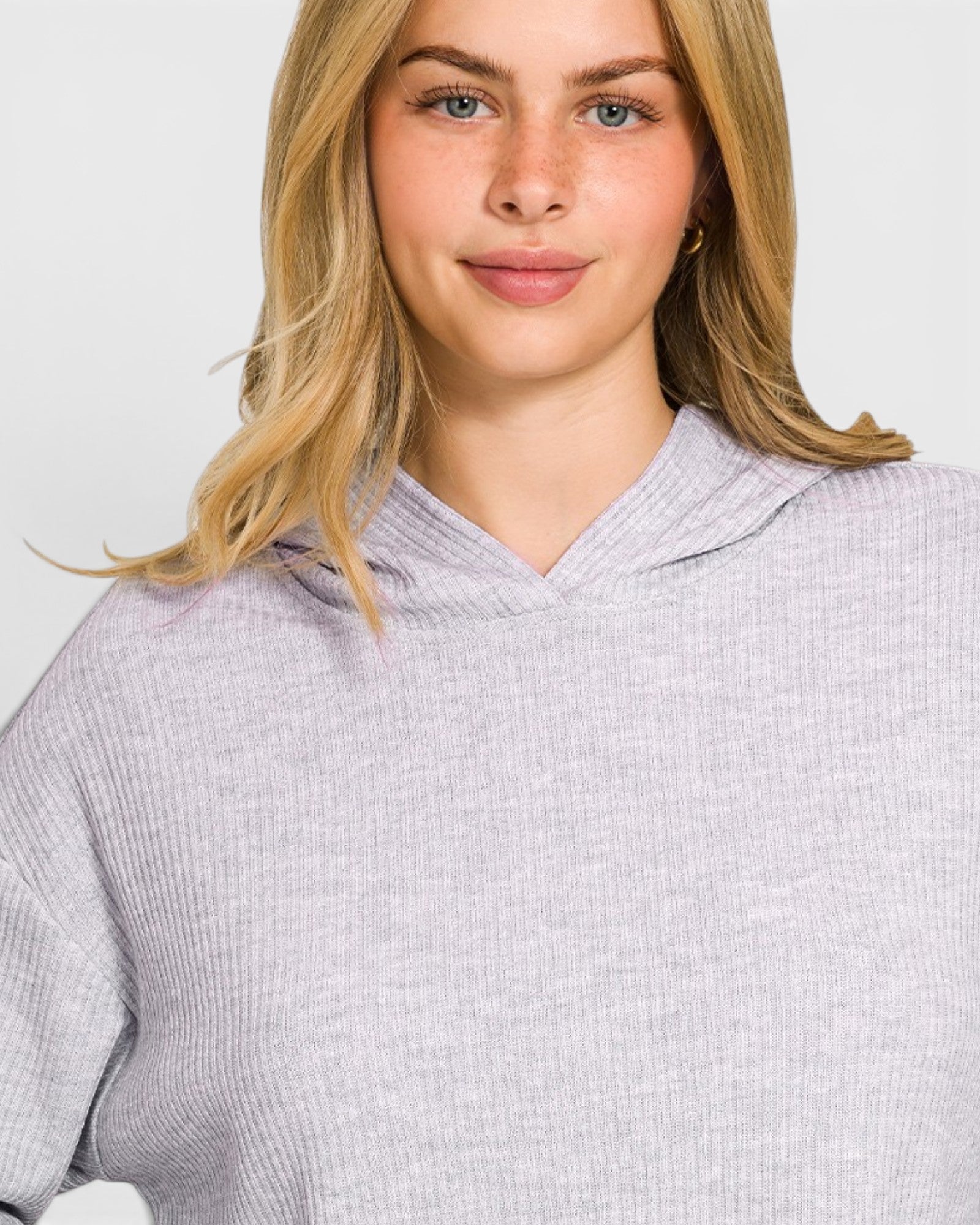 Woman wearing a light gray textured sweater against a plain background