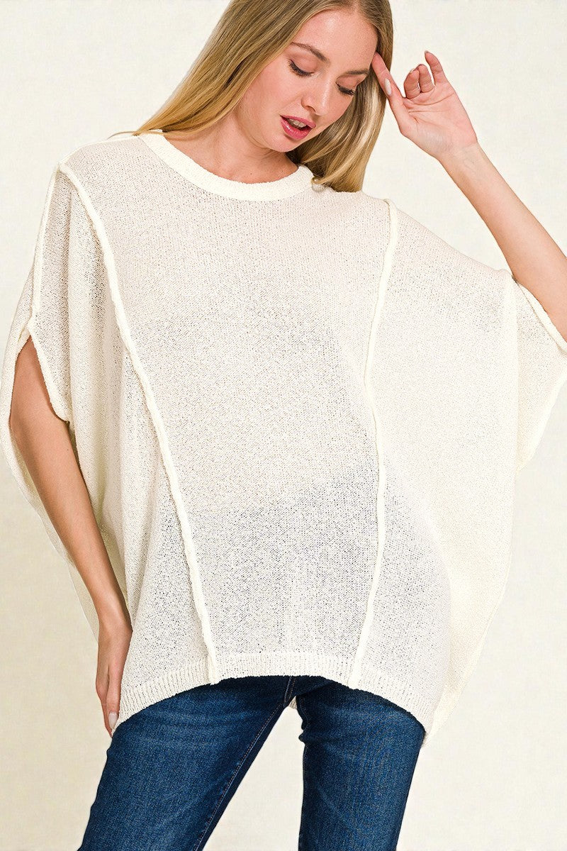 Woman wearing a white poncho over a blue outfit on a plain background