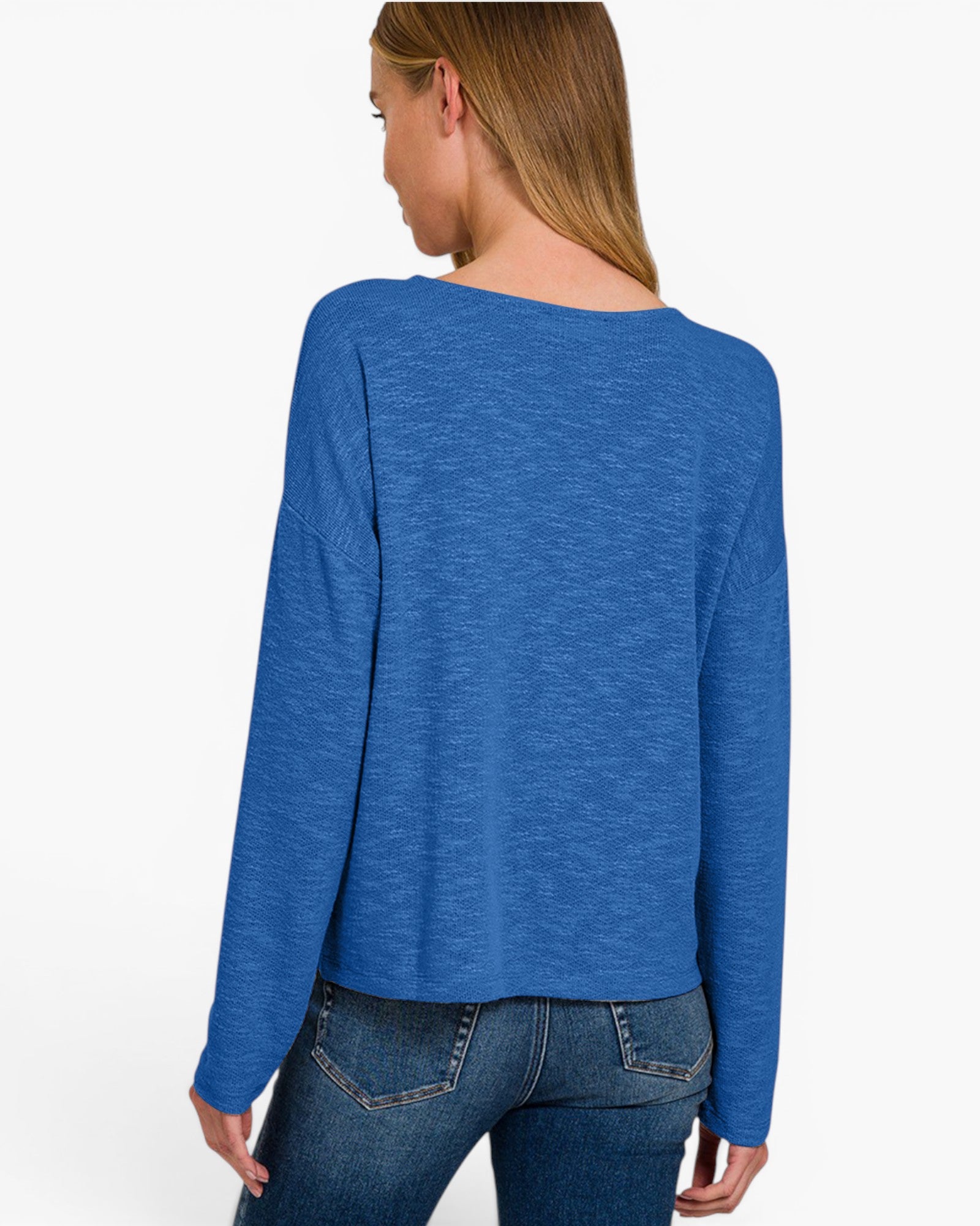 A woman shown from the back wearing a blue long-sleeve knit top and dark blue jeans against a plain white studio background.