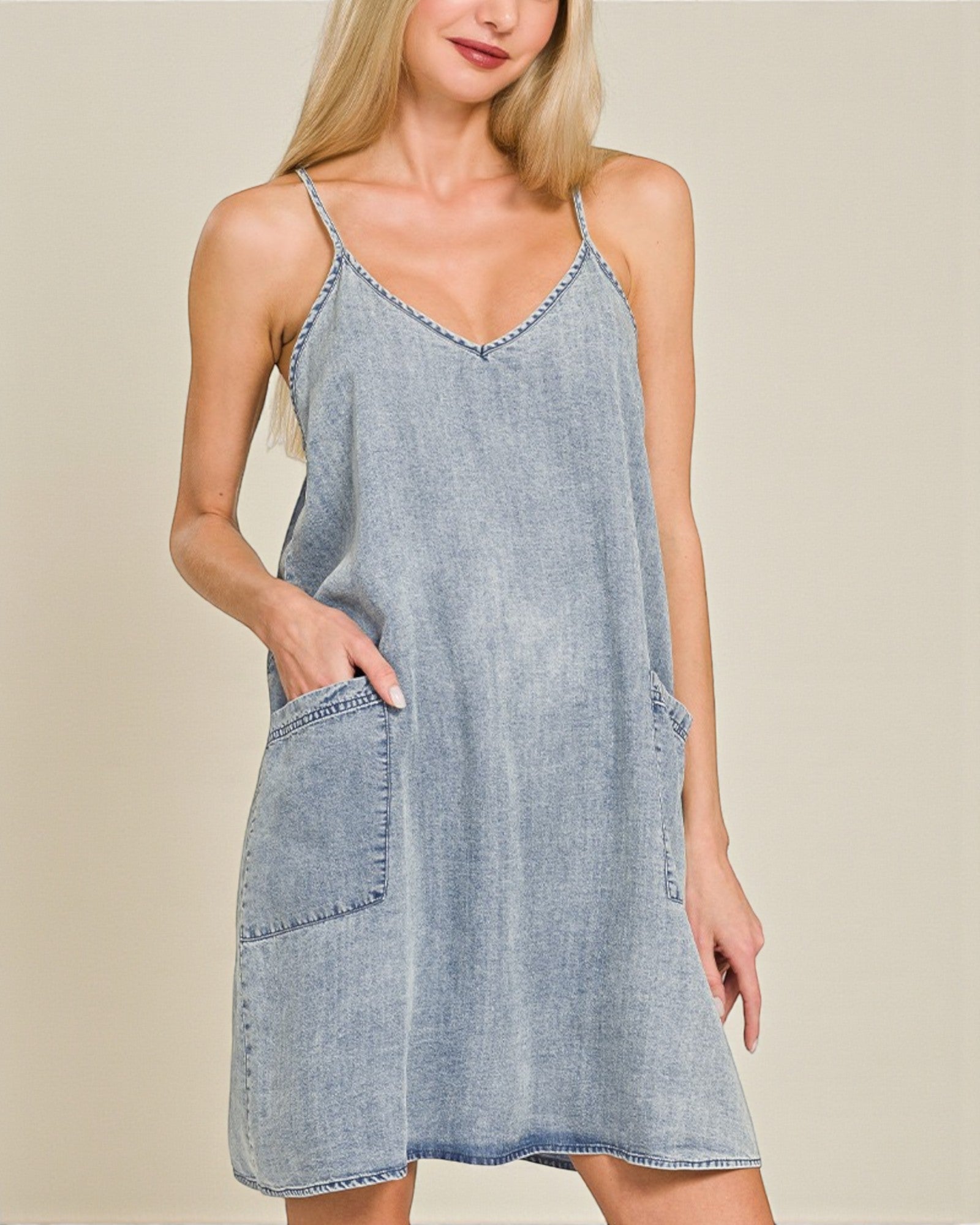 Woman wearing a light blue denim dress against a beige background