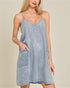 Woman wearing a light blue denim dress against a beige background