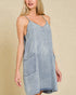 Woman wearing a light blue denim dress against a beige background