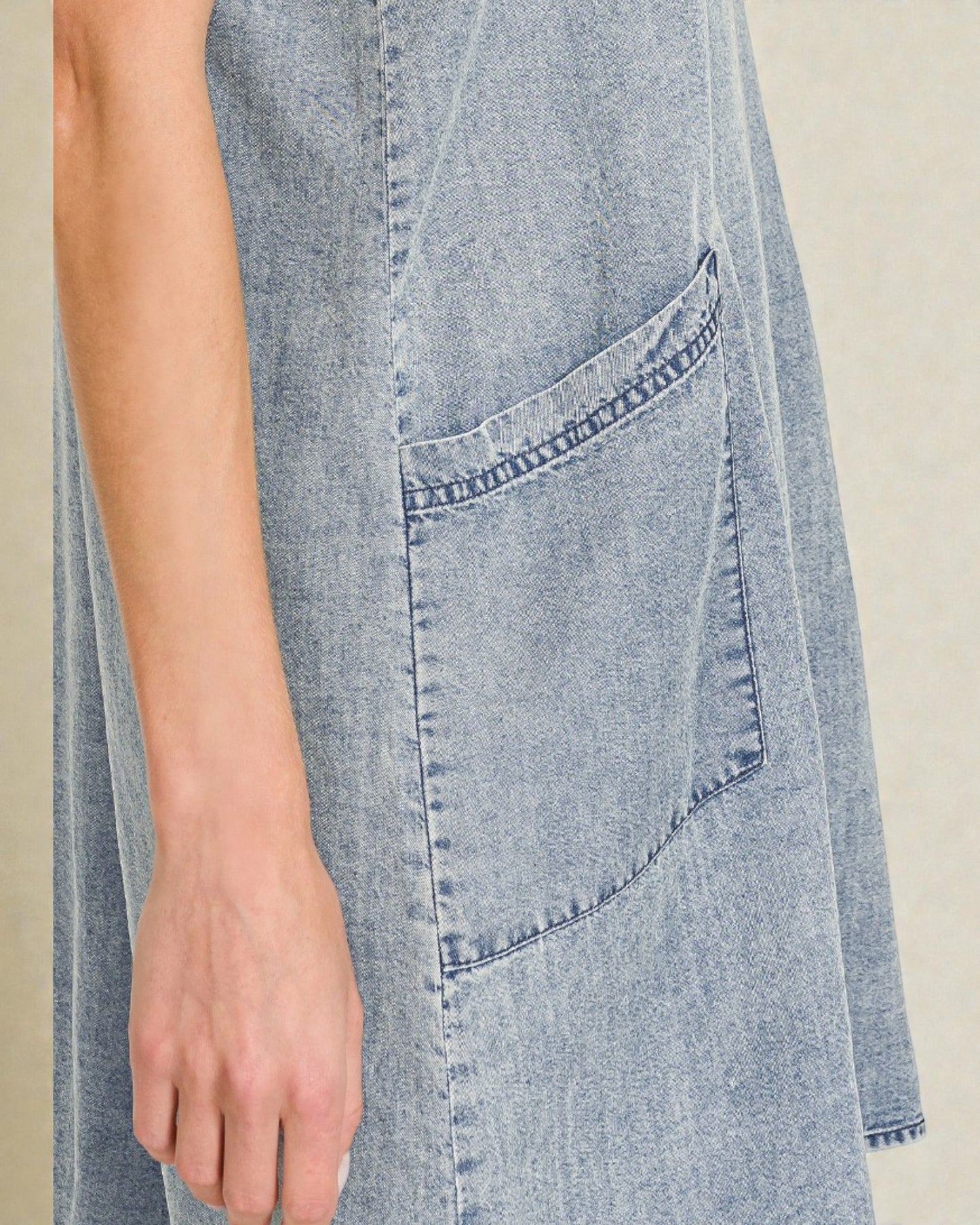 Close-up of a denim dress with a pocket on a neutral background