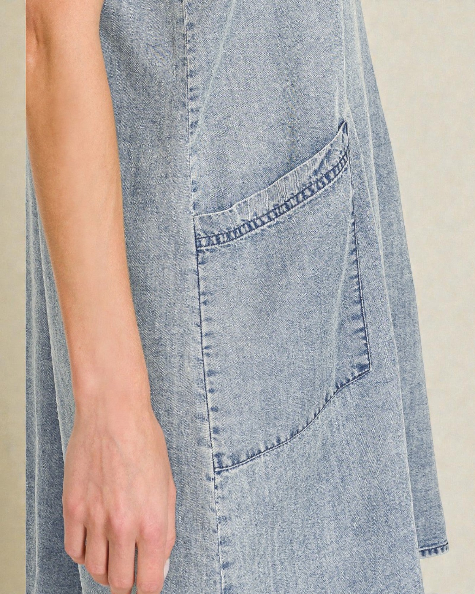 Close-up of a denim dress with a pocket on a neutral background