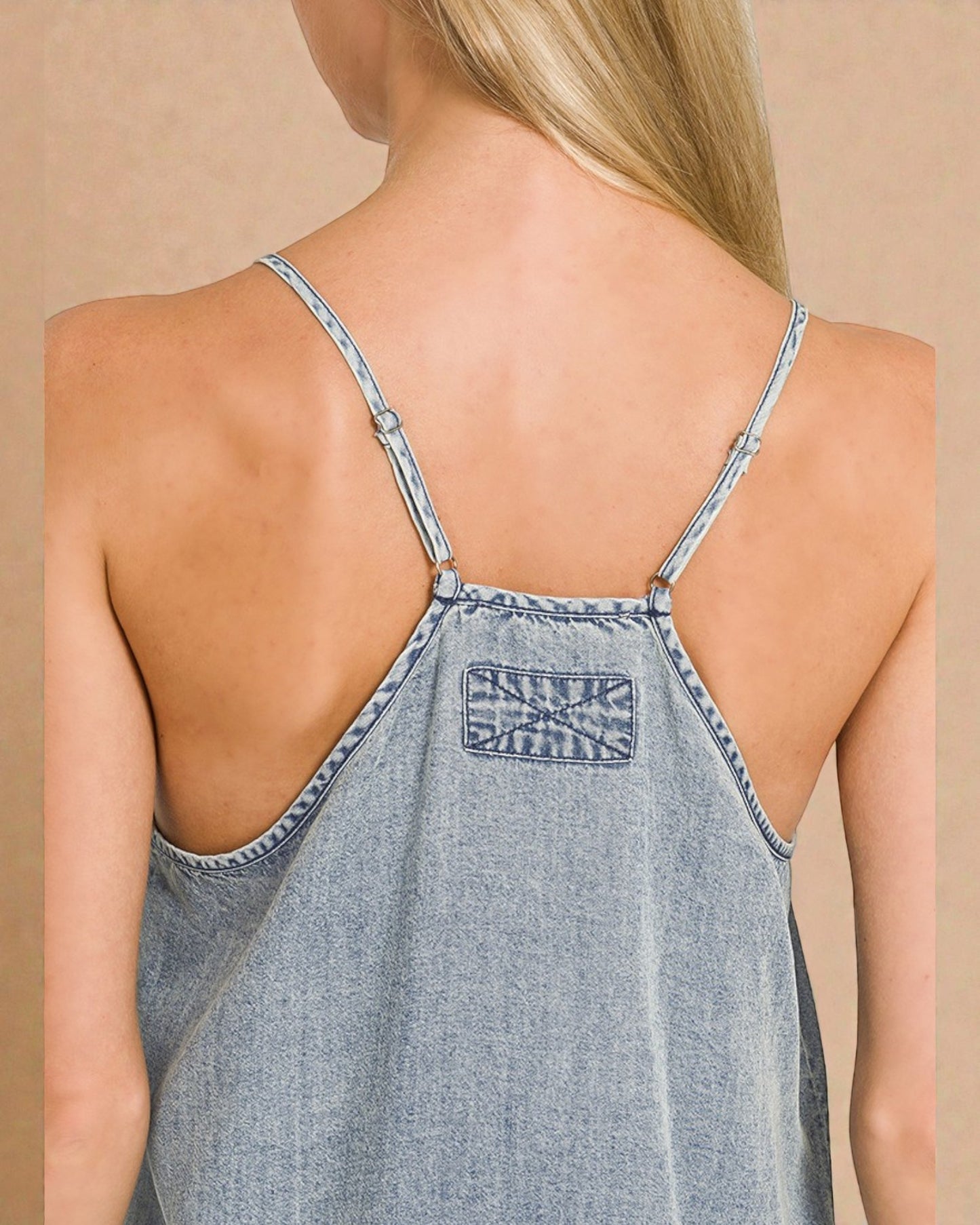 Denim dress with thin straps and a visible brand label on a beige background