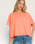 Woman wearing a coral oversized t-shirt with a pocket on a plain background