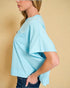 Light blue top worn by a person on a beige background
