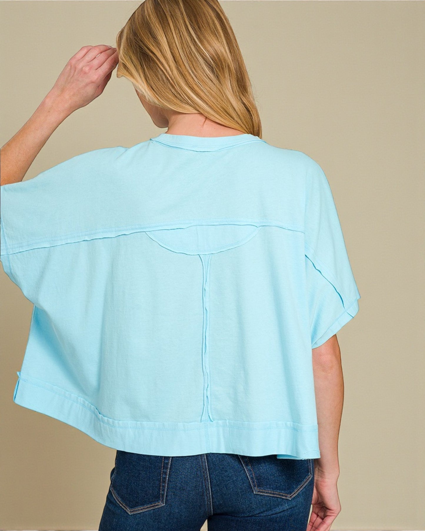 Light blue top worn by a person on a beige background