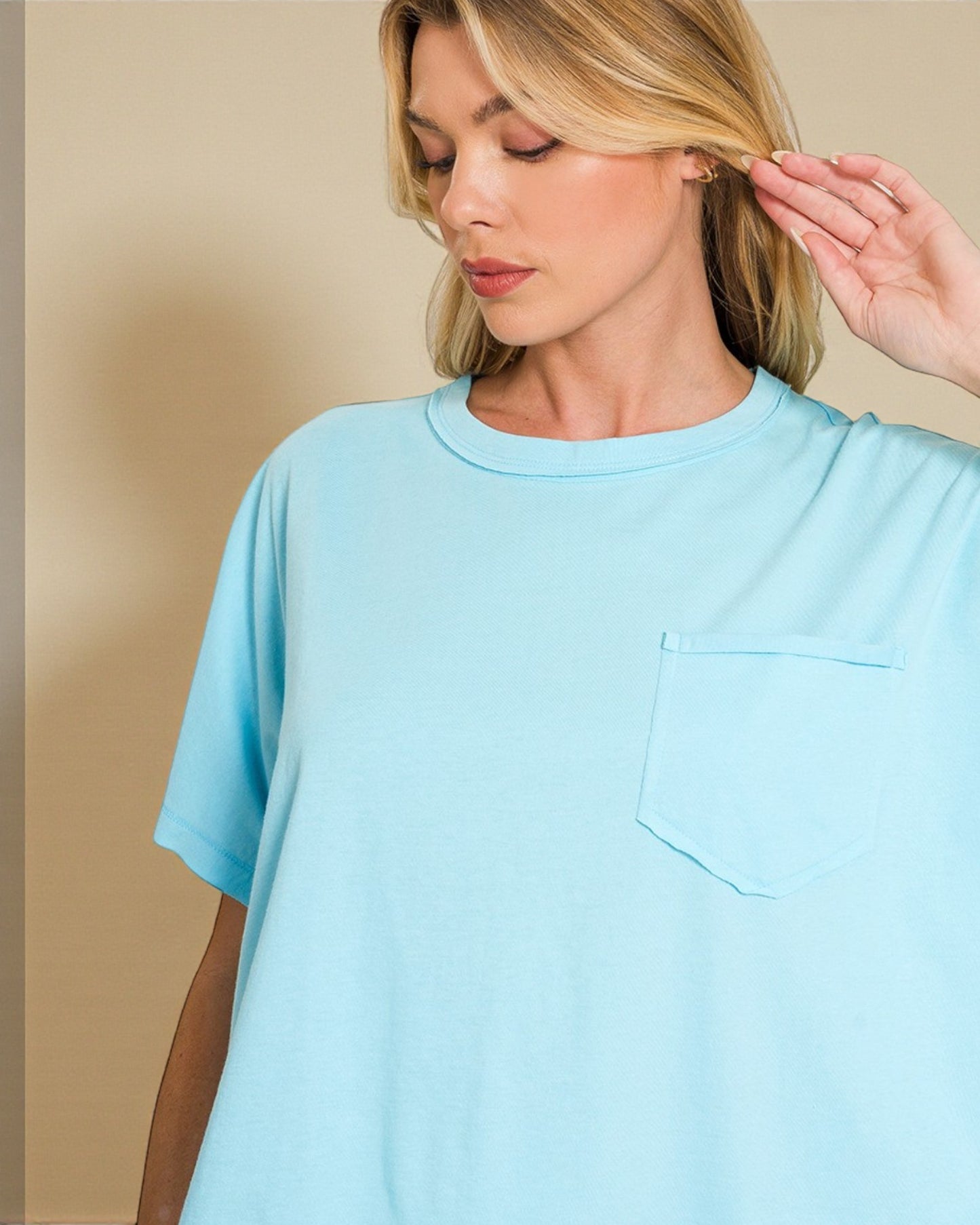 Woman wearing a light blue t-shirt against a beige background