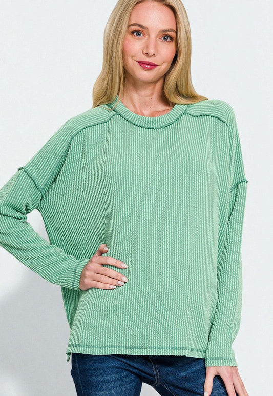 Woman wearing a green ribbed sweater against a white background