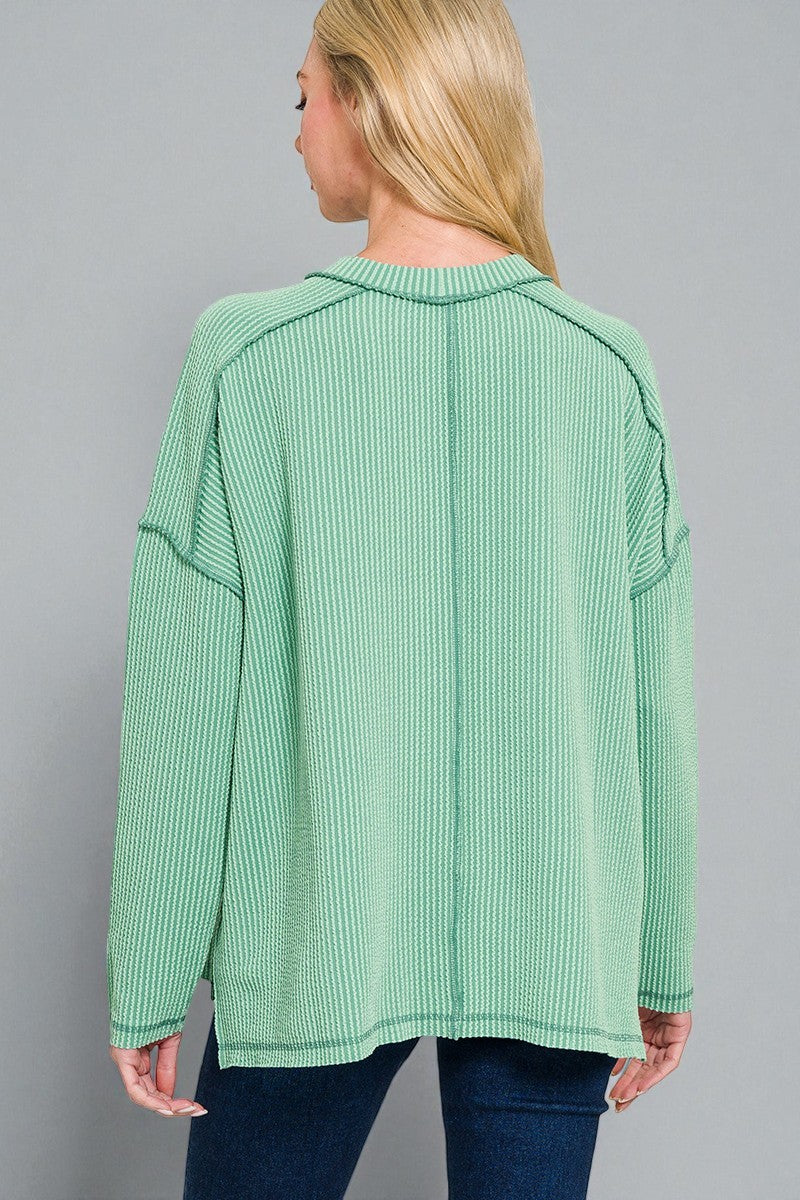 Woman wearing a green ribbed sweater against a gray background