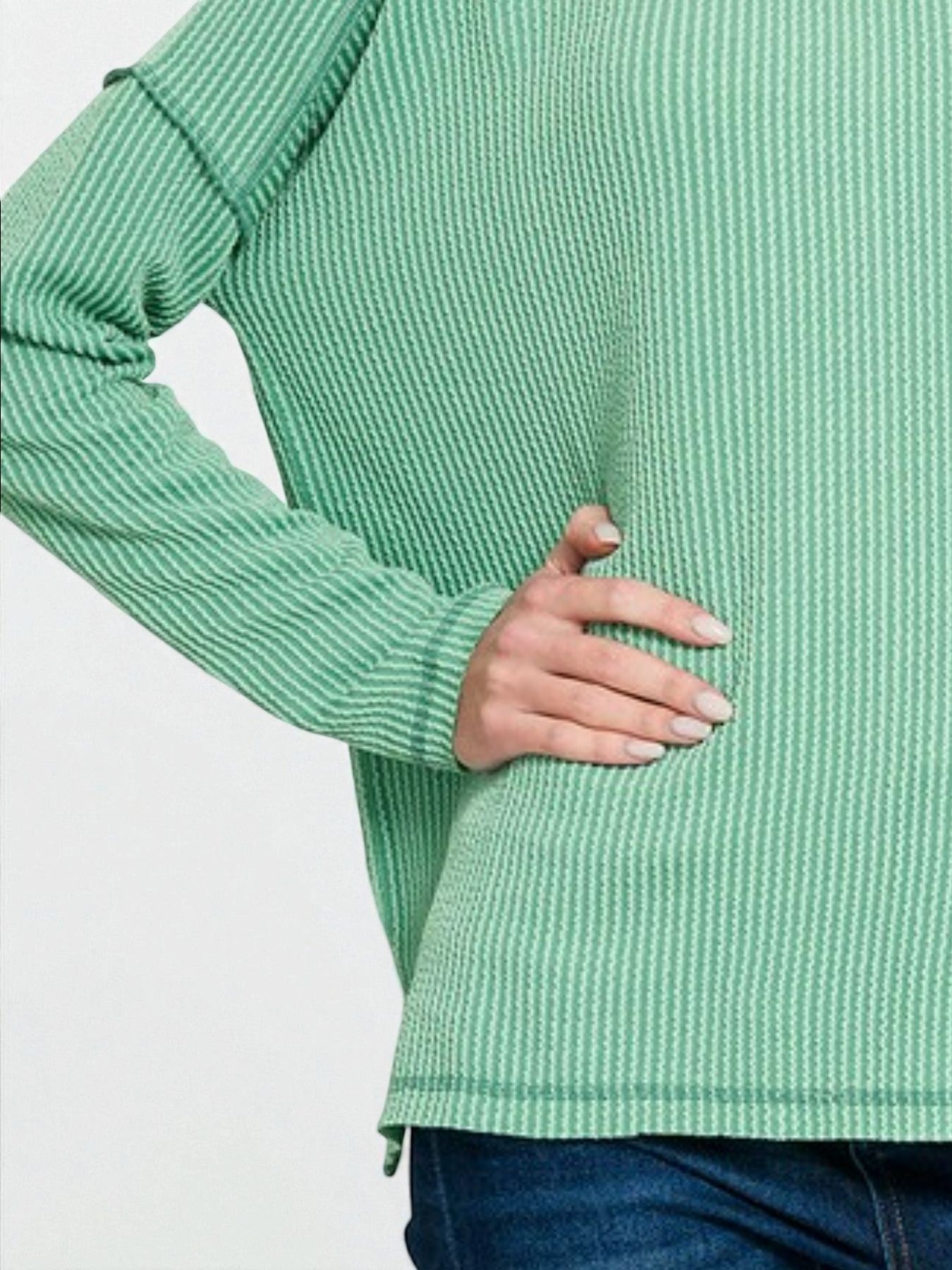 Green ribbed sweater worn by a person on a white background