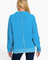 A woman viewed from the back wearing a bright turquoise blue knit sweater with a central fringe detail and frayed trim along the sleeves and hem, paired with dark blue jeans against a plain white background.