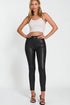 Woman wearing a white crop top and black leather pants on a white background