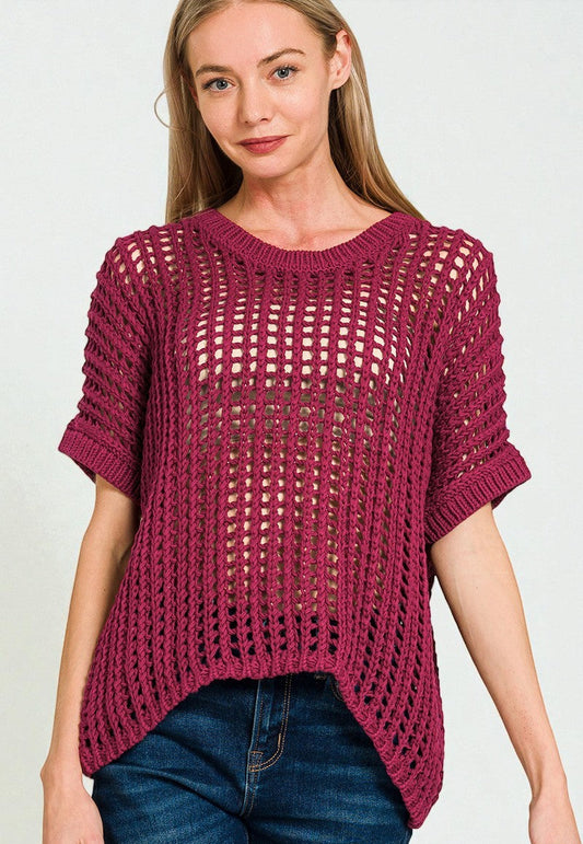 Woman wearing a maroon knitted sweater and blue jeans on a white background