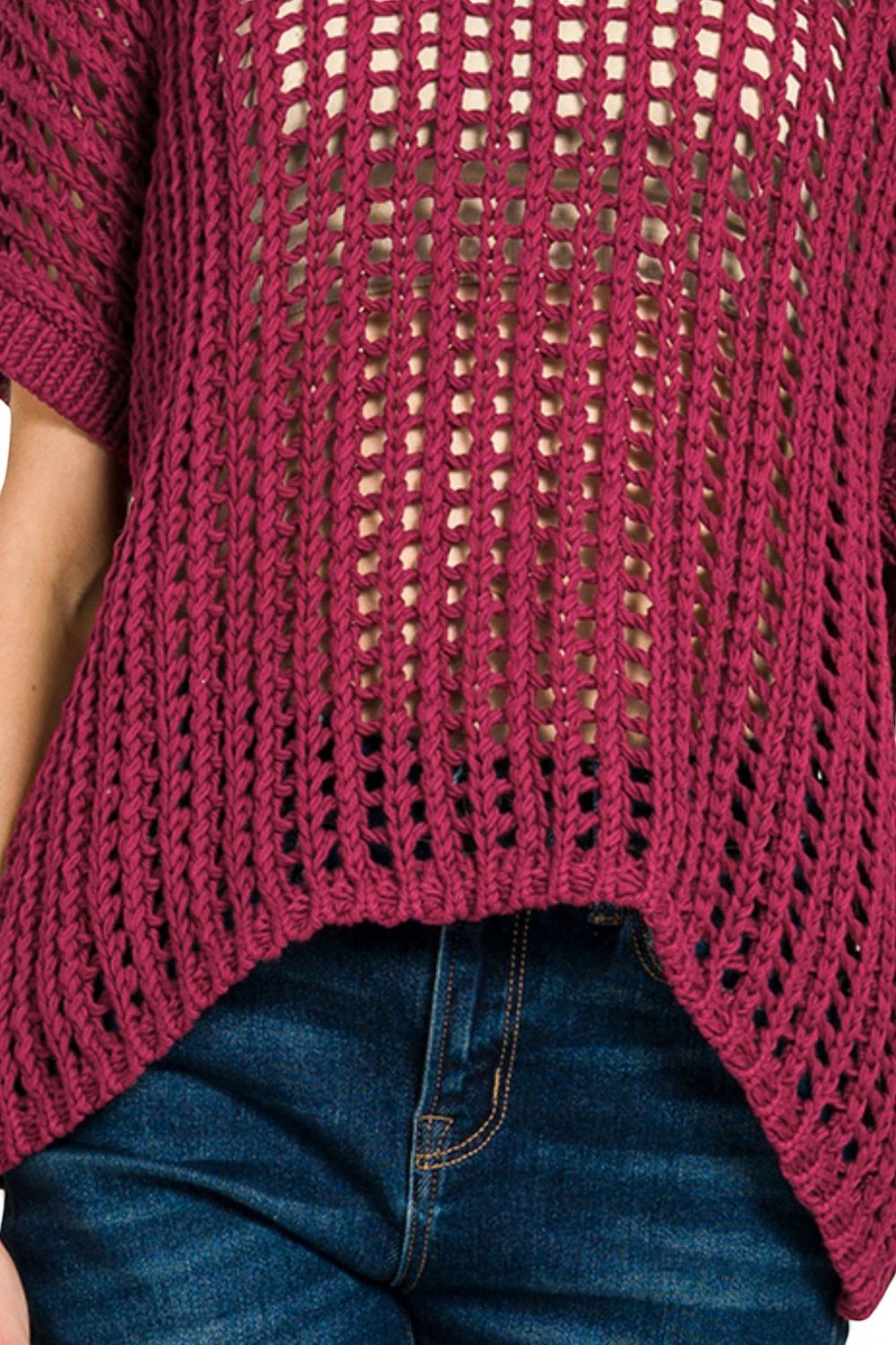 Close-up of a person wearing a maroon knitted sweater and blue jeans.