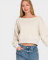 Woman wearing a beige sweater and blue jeans on a white background