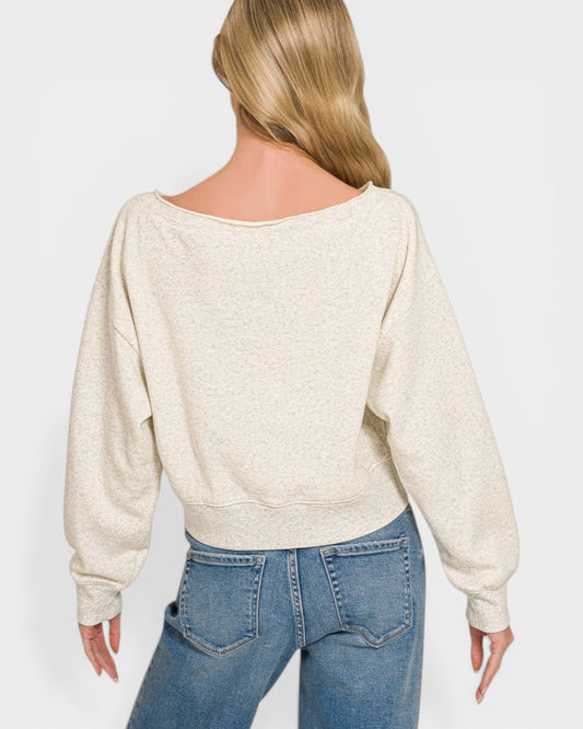 Person wearing a beige sweater and blue jeans on a plain background