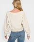 Person wearing a beige sweater and blue jeans on a plain background