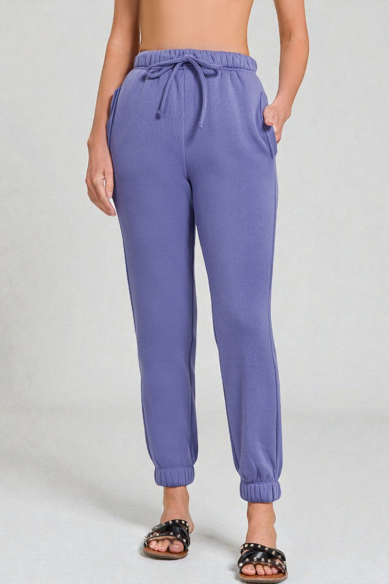 Purple sweatpants worn by a person on a plain background