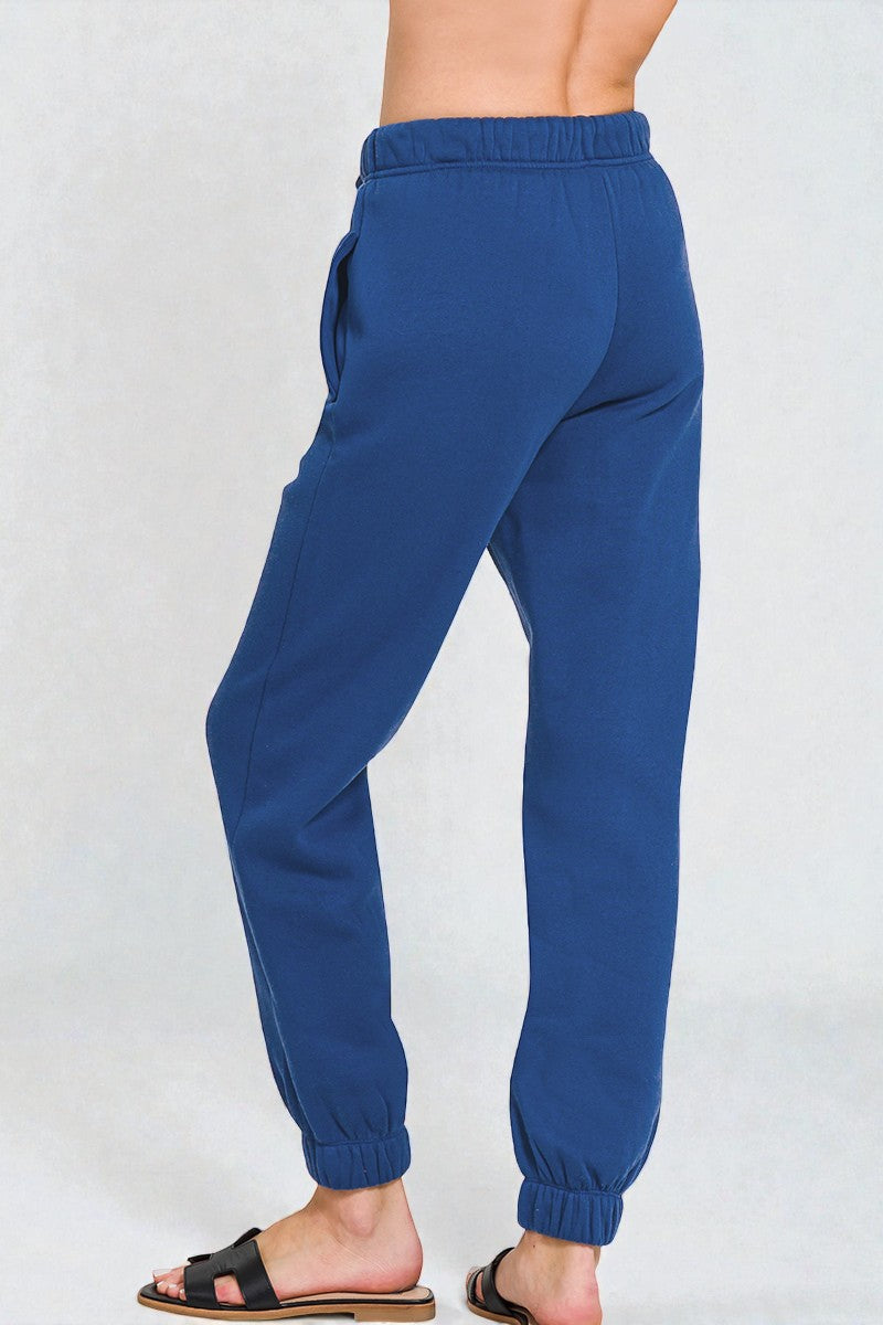 Blue sweatpants worn by a person on a white background