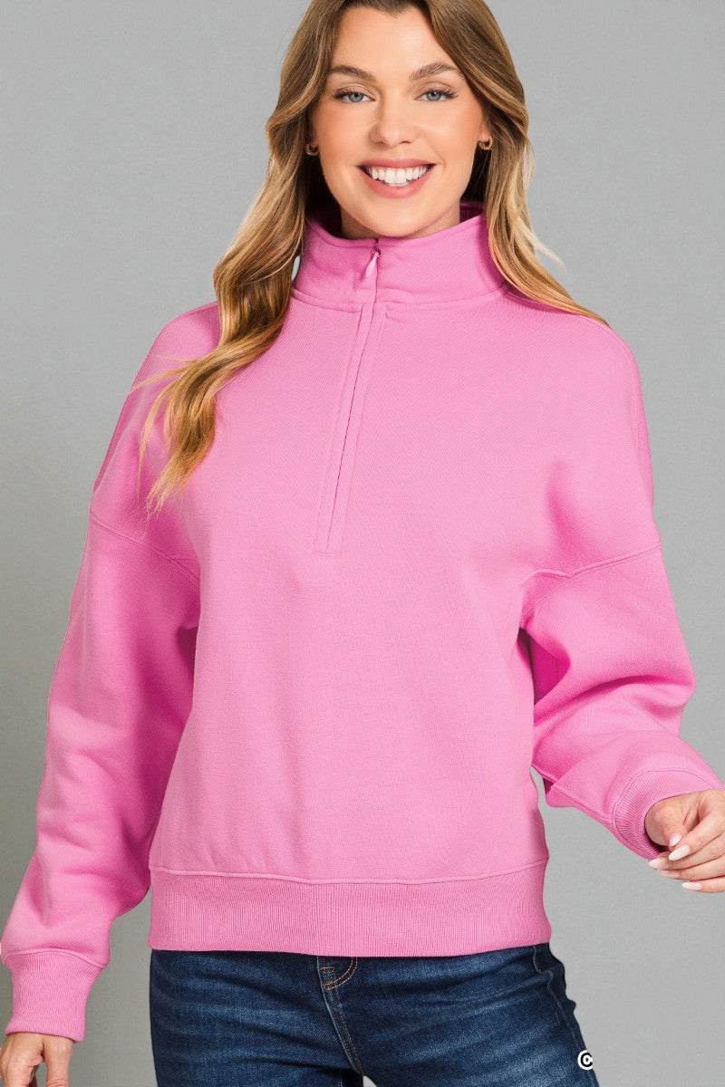 Woman wearing a pink half-zip sweatshirt against a gray background