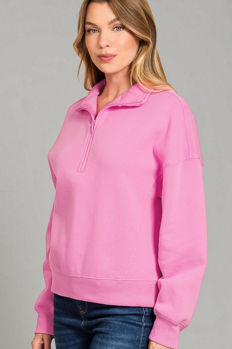 Woman wearing a pink pullover with a zipper on a gray background