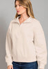 Woman wearing a beige pullover with a zipper on a gray background