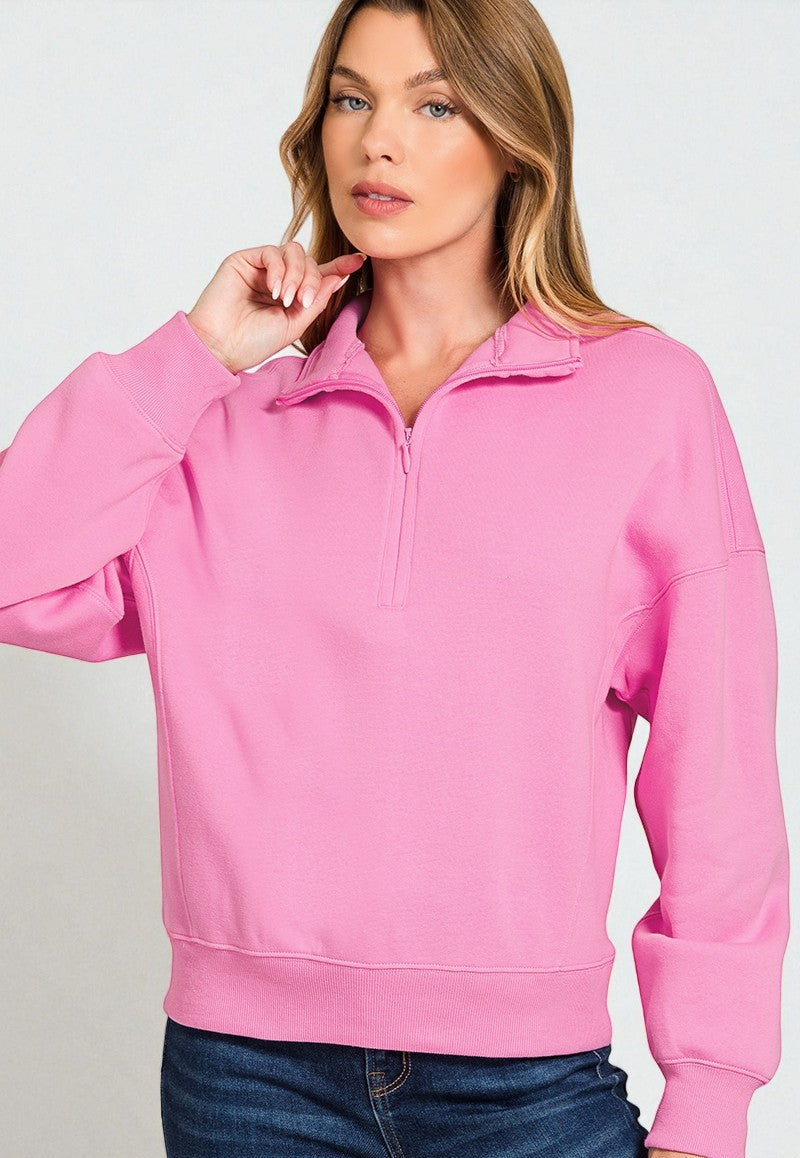 Woman wearing a pink half-zip sweatshirt against a light gray background