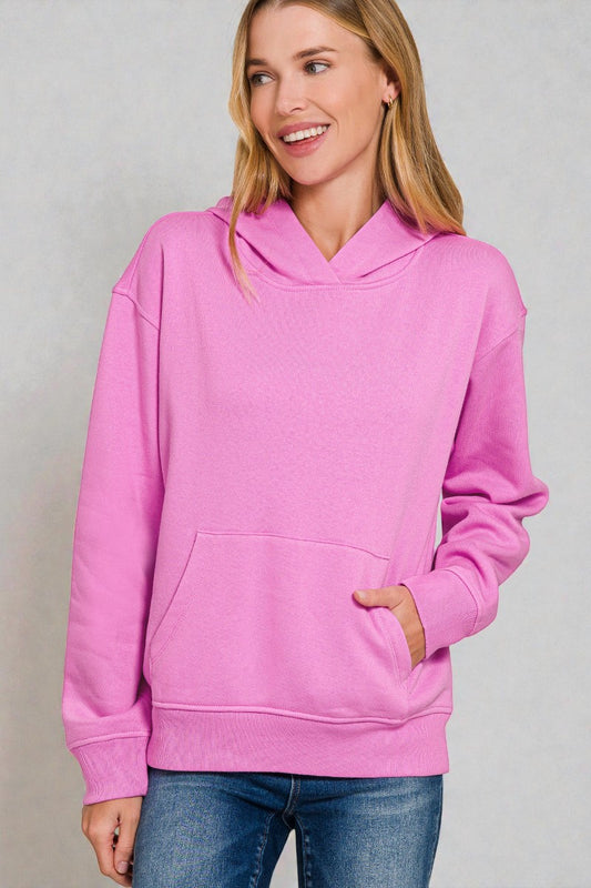 Woman wearing a pink hoodie against a plain background