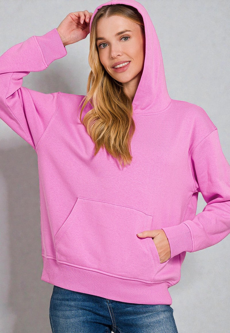 Woman wearing a pink hoodie against a gray background