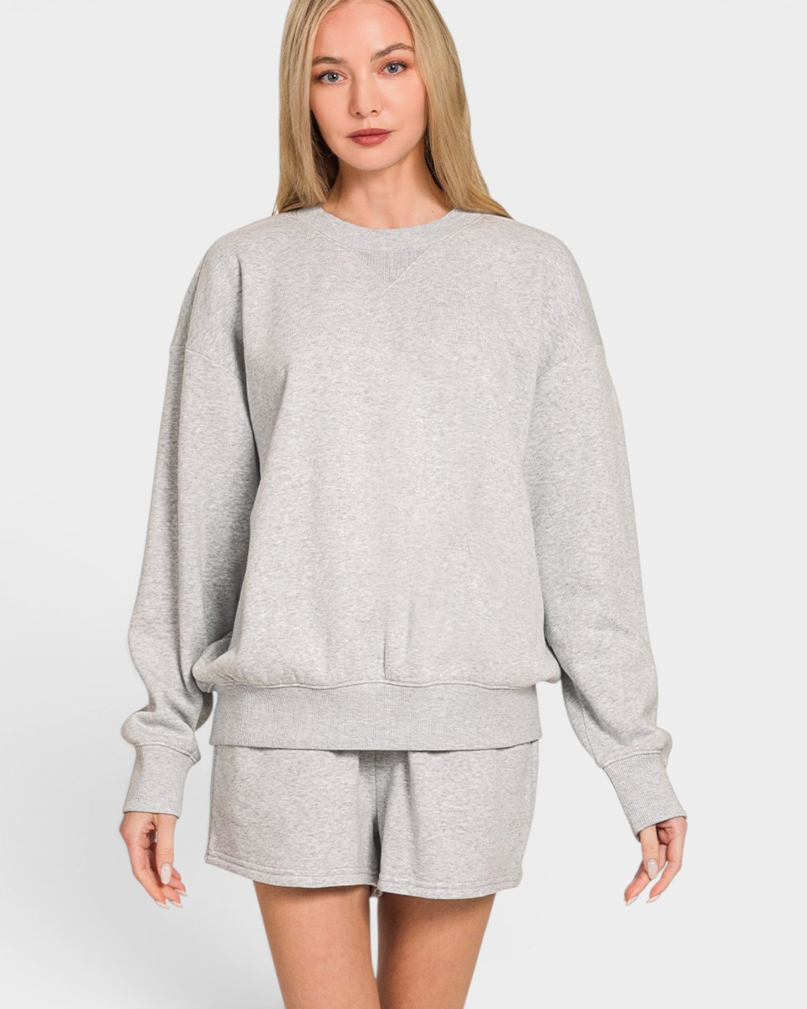 Woman wearing a gray sweatshirt and shorts set on a white background