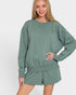 Woman wearing a green sweatshirt and shorts set on a white background