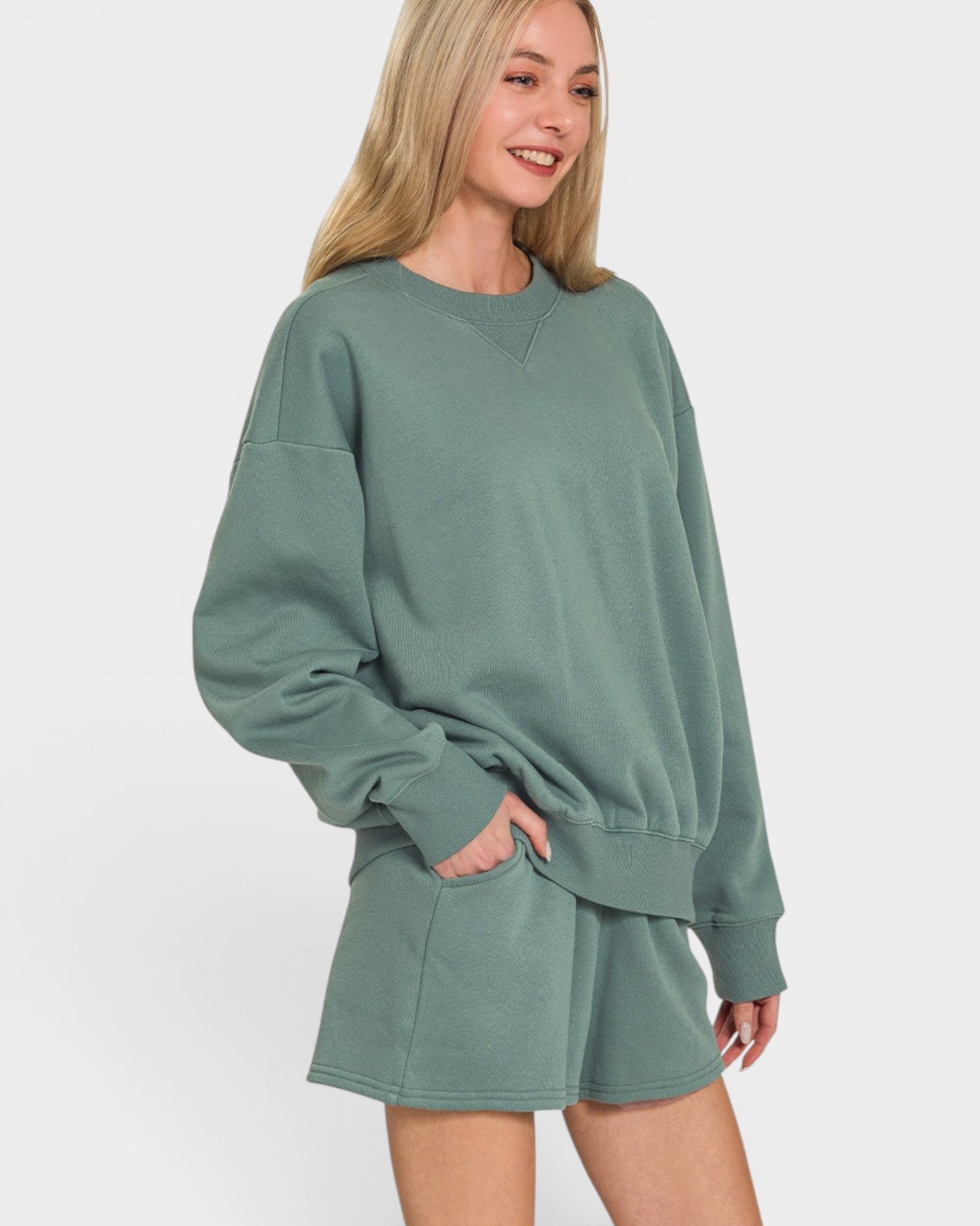 Woman wearing a green oversized sweatshirt and shorts set on a white background